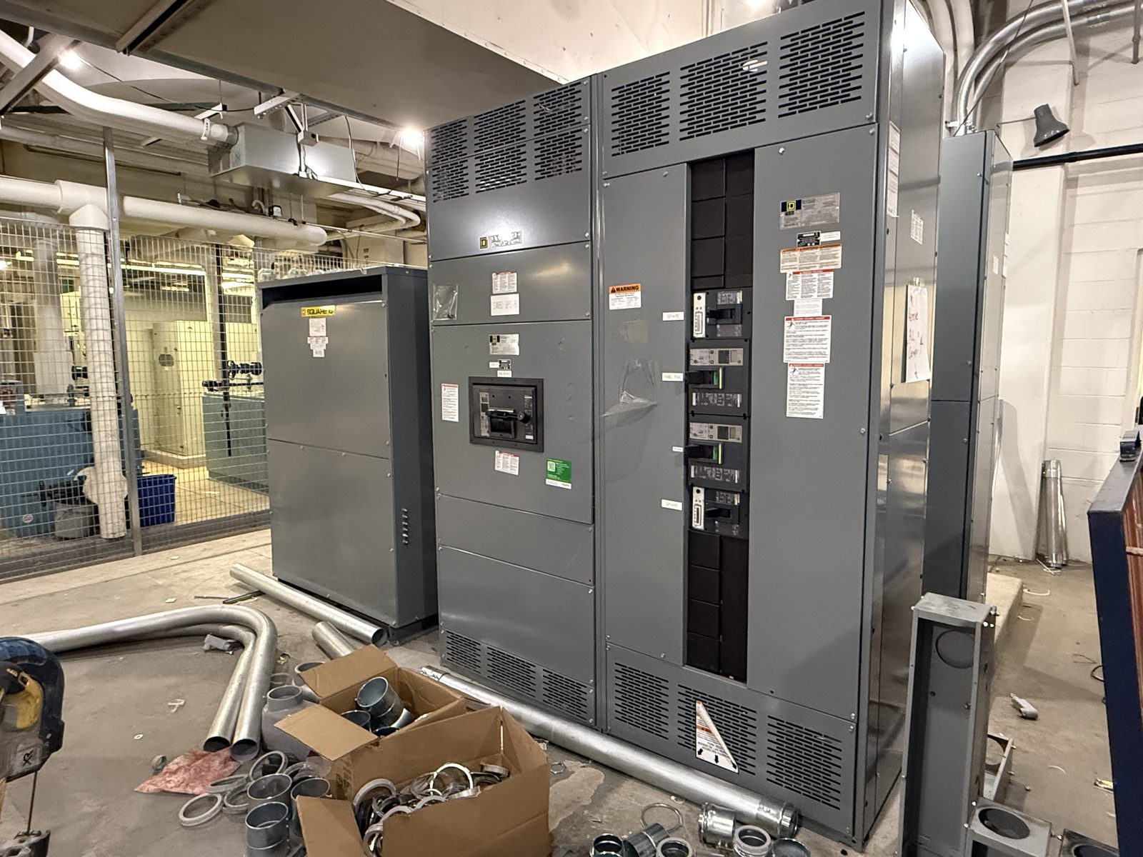 Used Square D low voltage switchgear lineup with main breaker and molded case branch breakers, staged indoors during an electrical room demolition